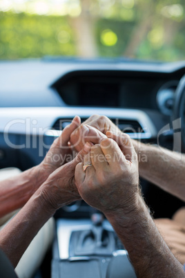 Senior couple holding hands in car