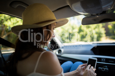 Young woman using phone in car
