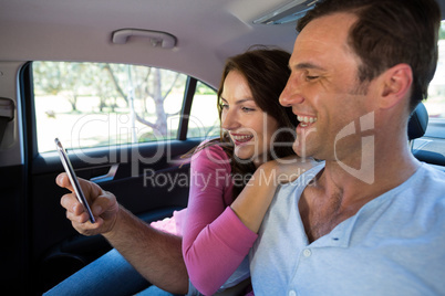 Happy couple using mobile phone in car