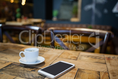Close up of mobile phone and tea cup on table