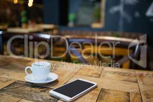 Close up of mobile phone and tea cup on table