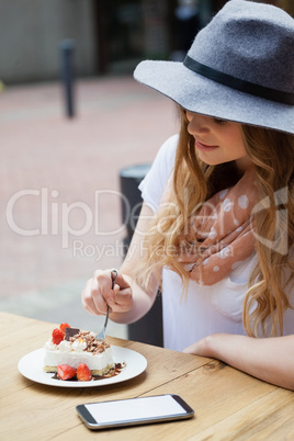 Woman wearing hat eating brakfast at table