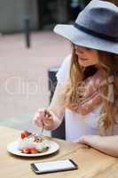 Woman wearing hat eating brakfast at table