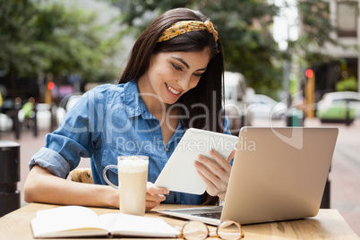 Woman holding tablet while sitting at cafe