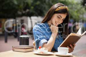 Woman reading book while sitting at cafe