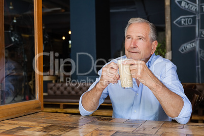 Senior thoughtful man holding cold coffee