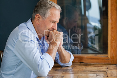 Thoughtful senior man sitting at table