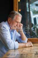 Thoughtful senior man looking away while sitting at table