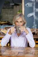 Senior woman drinking coffee while sitting at table