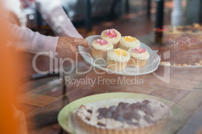 Close up of senior woman holding cupcakes in plate