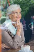 Senior woman looking away while sitting at table