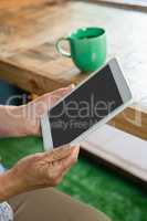 Close up of senior  woman holding tablet while drinking coffee