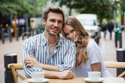 Portrait of smiling couple sitting at sidewalk cafe