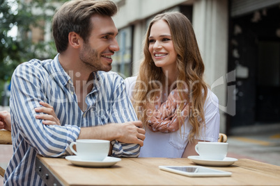 Couple sitting by table at sidewalk cafe