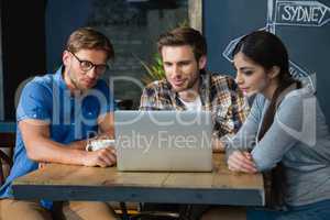 Friends using laptop while having coffee