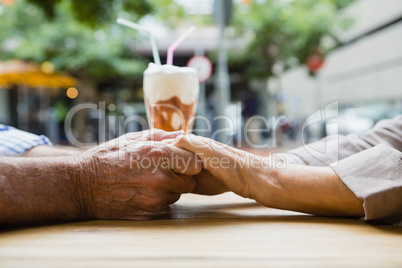Senior couple holding hands in outdoor cafÃ?Â©