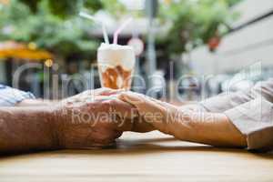 Senior couple holding hands in outdoor cafÃ?Â©