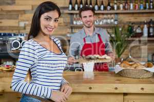 Portrait of smiling woman with waiter standing in background