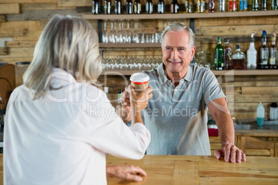 Senior man serving coffee to woman