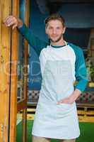 Portrait of smiling waiter standing with hand in pocket