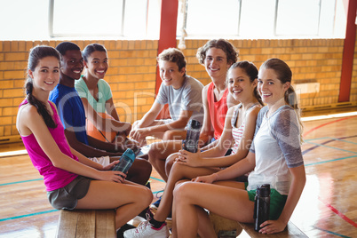 Smiling high school kids relaxing in basketball court