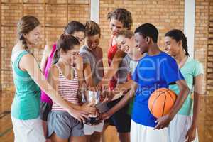Excited high school kids holding trophy in basketball court