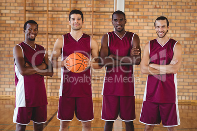 Confident basketball players holding basketball in court