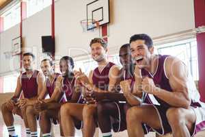 Excited basketball player sitting on bench