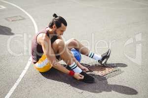 Basketball player tying shoe laces while sitting