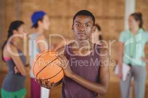High school boy standing with basketball in the court