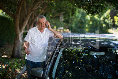 Senior man using phone by car