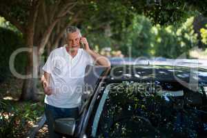 Senior man using phone by car