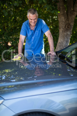 Senior man cleaning car in yard