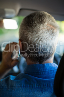 Senior man talking on phone while driving car