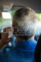 Senior man talking on phone while driving car