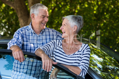 Senior couple leaning on car door