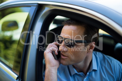 Young man talking on phone while driving car
