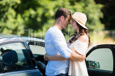 Young couple embracing by car on sunny day