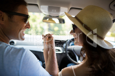 Happy couple holding hands while traveling in car