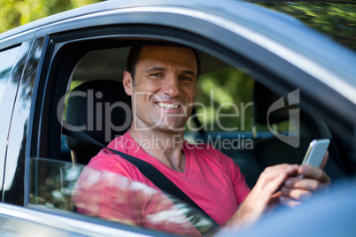 Portrait of smiling man using mobile phone in car