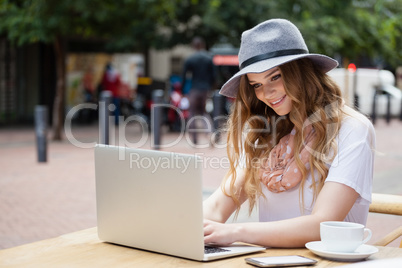 Woman wearing hat using digital laptop at table