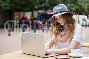 Woman wearing hat using digital laptop at table
