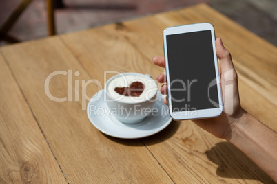 Close up of woman photographing coffee cup on table