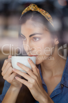 Close up of woman looking away while drinking coffee