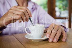 Midsection of senior woman stirring coffee