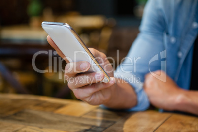 Cropped image of man using smart phone at table