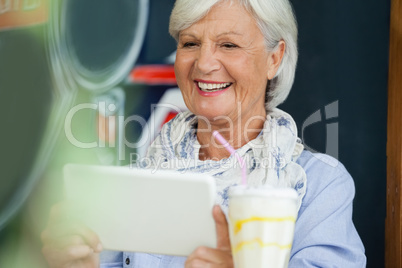 Happy woman holding digital tablet while sitting at cafe