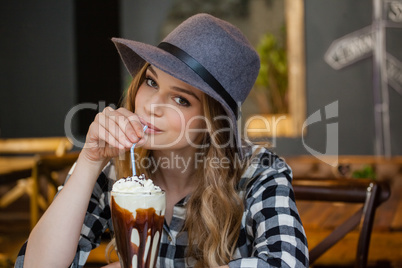 Portrait of woman wearing hat drinking cold coffee