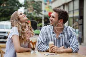 Happy couple laughing while sitting at sidewalk cafe