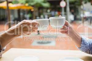 Hands of senior couple toasting coffee cups